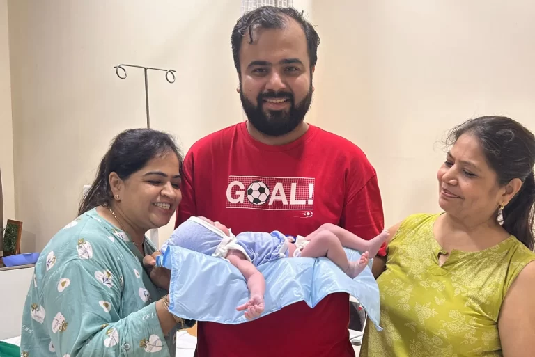 People posing with a baby gift set in a room1