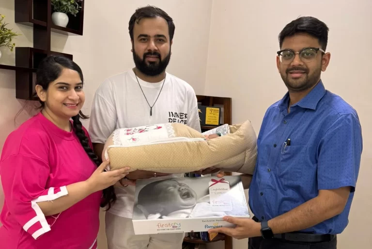 People posing with a baby gift set in a room2